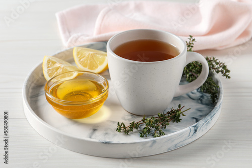 Aromatic herbal tea with thyme, honey and lemons on white wooden table