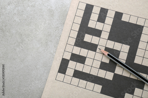 Blank crossword and pencil on old white table, top view. Space for text photo