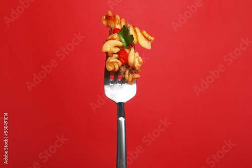 Fototapeta Naklejka Na Ścianę i Meble -  Fork with tasty pasta on red background