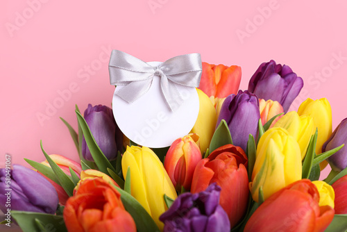 Bouquet of beautiful colorful tulips with blank card on pink background  closeup. Birthday celebration
