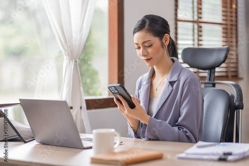 Happy Young Asian woman using laptop while working at home with documents. online documentation calculator to calculate the numbers, finance accounting office concept