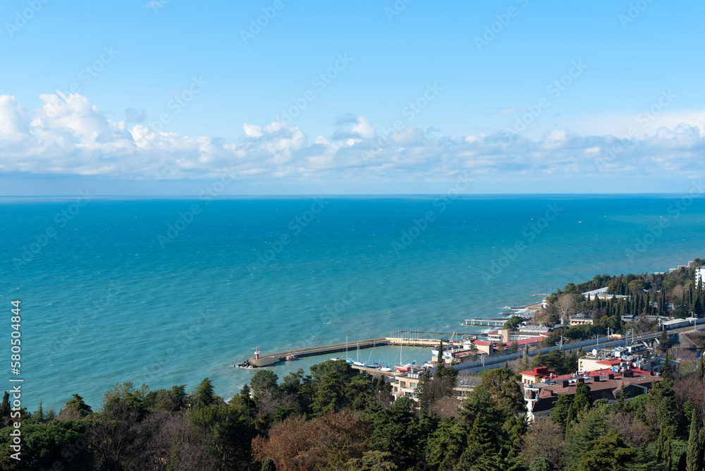 View of Sochi city on a sunny winter day with bright blue sky with white clouds and blue sea. Nature background with selective focus. Travel concept