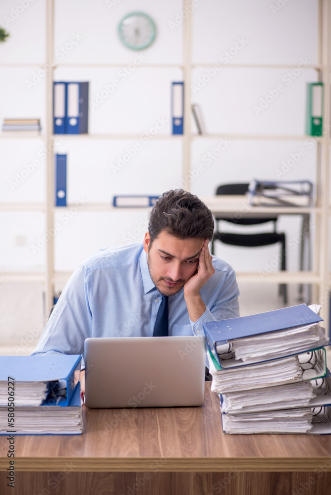 Fototapeta premium Young male employee and too much work in the office