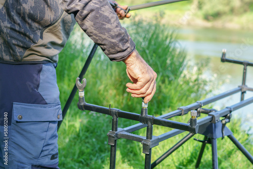 angler setting up a rod holder tripod for carp fishing