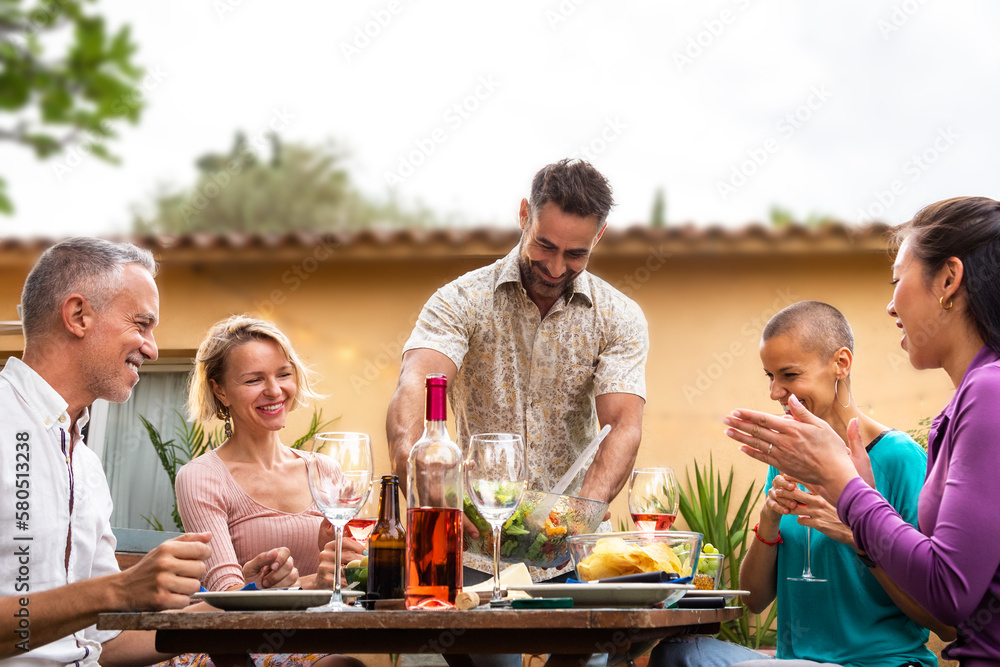 Man serving food to friends during outdoor garden dinner party. Friends having fun. Man serving food to friends during outdoor garden dinner party. Friends having fun.