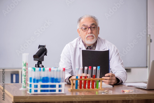 Old male teacher chemist sitting in the classroom