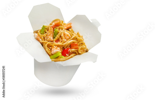 Asian ramen noodles with shrimp, vegetables, soy sauce and spring onion scallions in white carton or cardboard takeaway delivery box. Fast delivery, street food concept in take-out box
