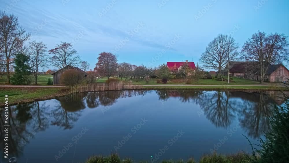 Timelapse of sunset at lake on a green meadow with trees and wooden houses and clouds advancing on the horizon. Timelapse of sunset at lake on a green meadow with trees and wooden houses and clouds advancing on the horizon.