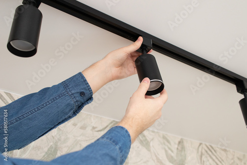 A man install a spot track LED light in the ceiling.