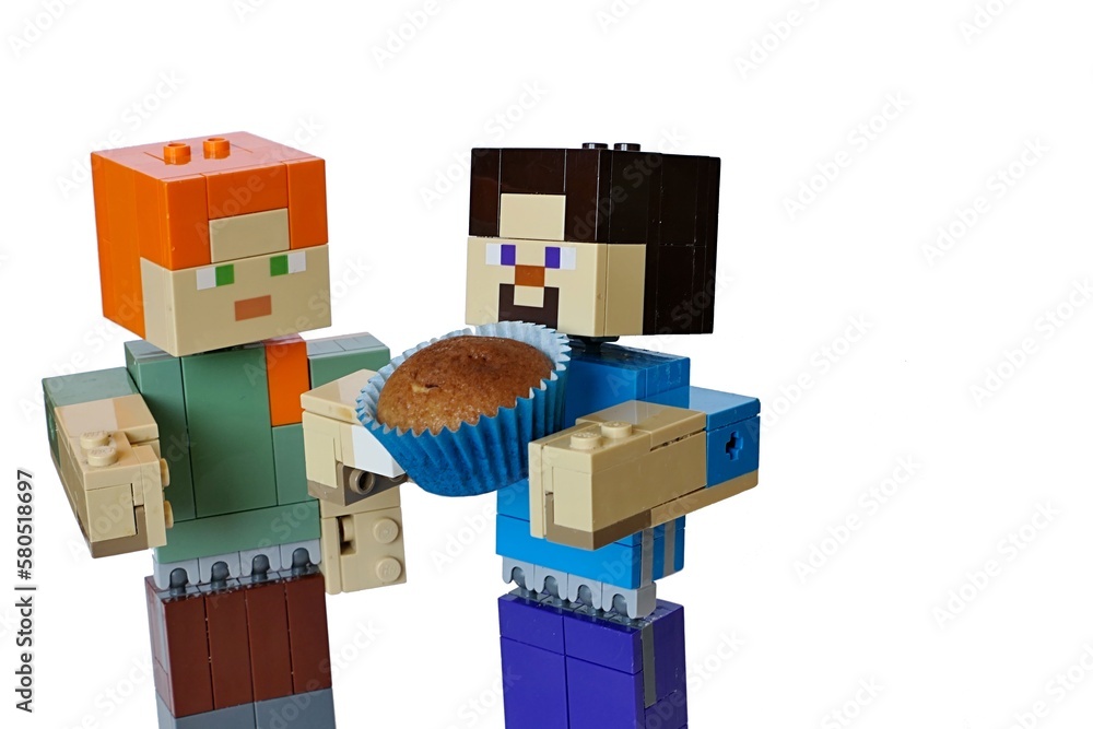 Naklejka premium LEGO Minecraft figures o Steve and Alex, Steve holding baked brown muffin cake in blue paper cup. White background.