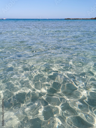 Fig Tree Bay beach, crystal clear water, white sand at the bottom, small island off the coast. © Elena