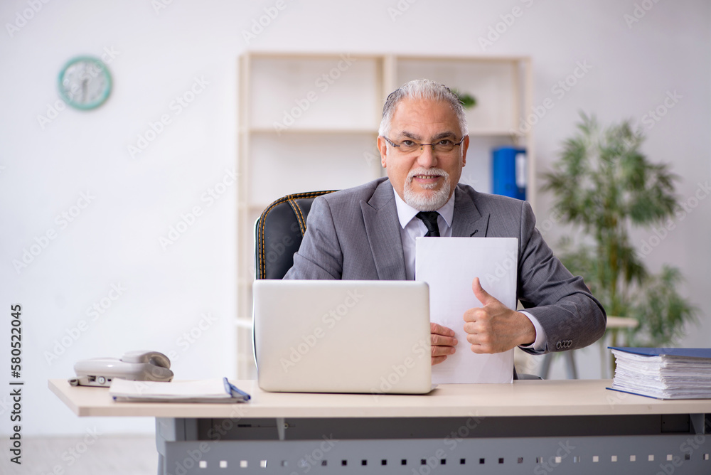 Old male employee working in the office Old male employee working in the office