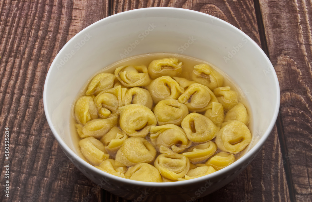 Traditional Italian Tortellini in brodo on wooden table. Traditional Italian Tortellini in brodo on wooden table.