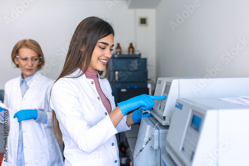 Two Research Scientists Talking about Programming Medical Equipment for Tests. Team of Professionals Doing Pharmaceutical Research in Modern Laboratory