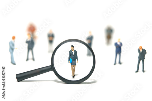 Miniature people toy figure photography. Women leader search. A businesswoman standing in the middle of male people crowd with magnifier glass. Isolated on white background