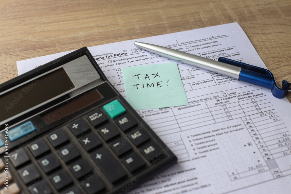 Tax time! Overhead view of work desk with keyboard, calculator, pen and income tax return form. Tax time! Overhead view of work desk with keyboard, calculator, pen and income tax return form.