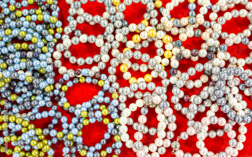 Natural sea pearls. A bunch of pearls on a red background, pearl strands close-up.