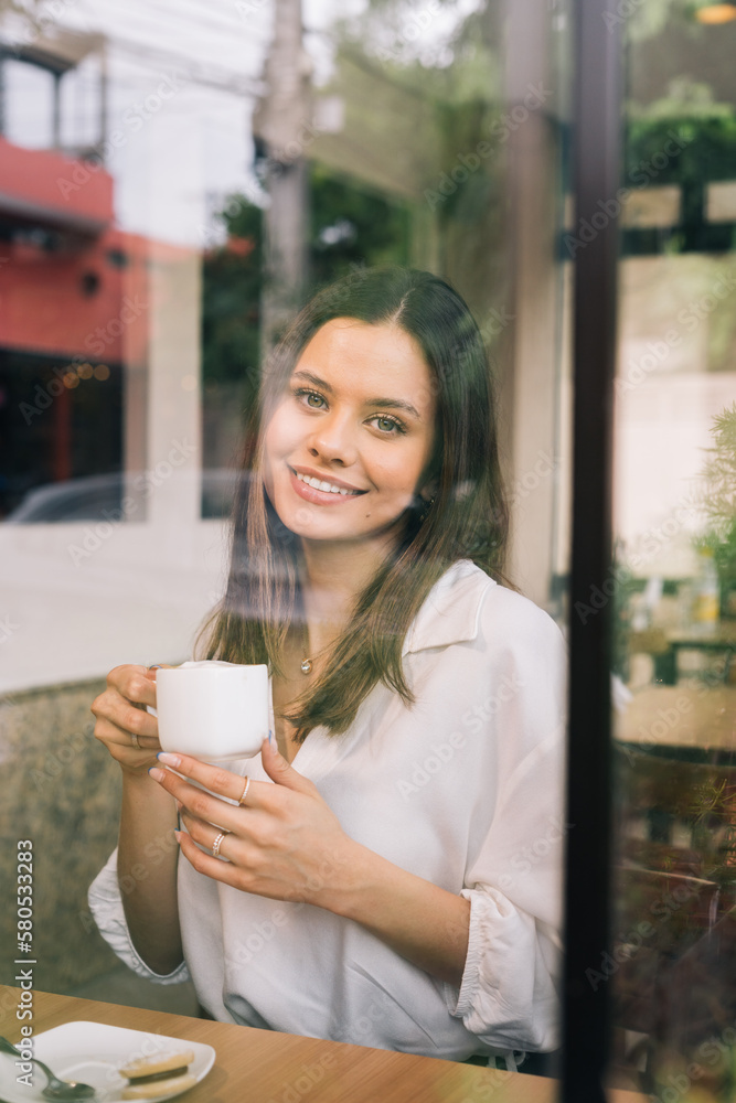 Vertical portrait of smiling young woman looking at camera. Successful business woman in office with space for text Vertical portrait of smiling young woman looking at camera. Successful business woman in office with space for text