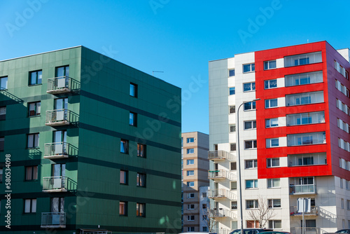 A newly built building in nice bright colors with apartments for sale.Red orange and green block of flats.Newly finished modern style apartment building in freshly renovated residential area.
