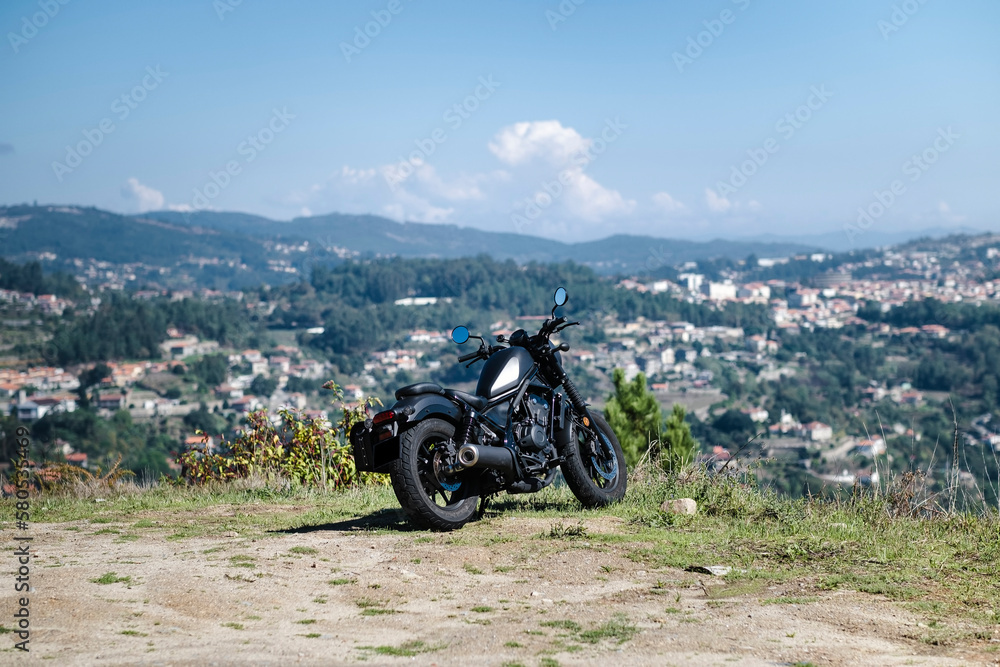 Mototourism. A motorcycle stands on the lawn overlooking the green valley.