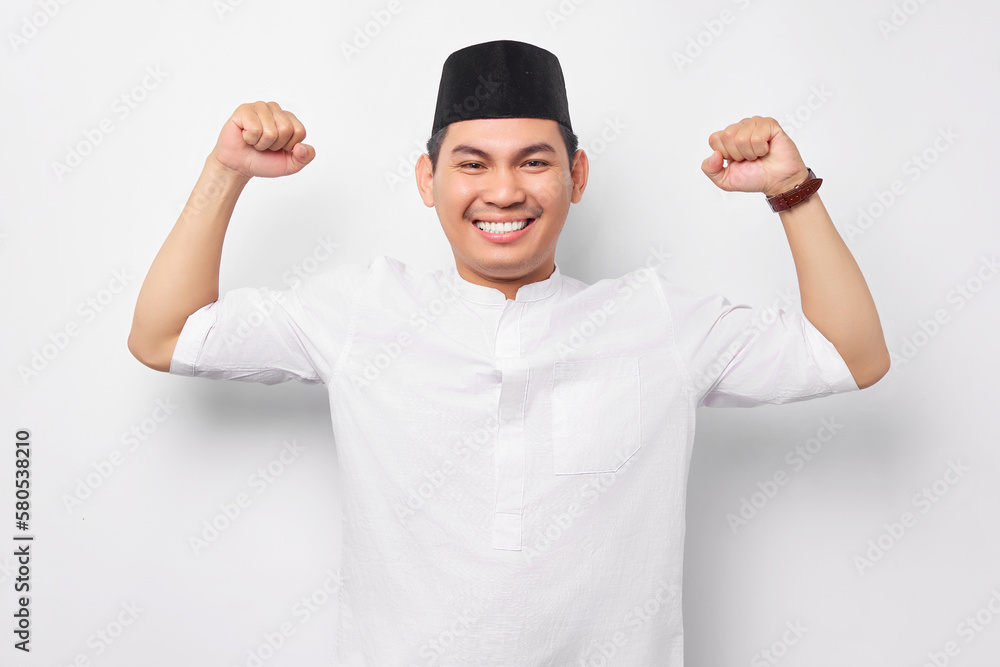 Fototapeta premium Handsome young Asian Muslim man showing arm muscle, confident and proud of power isolated on white background. People religious Islamic lifestyle concept