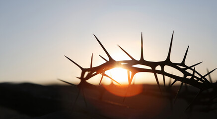 The cross and crown of thorns symbolizing the sacrifice and suffering of Jesus Christ and the red sunset, Passion Week and Lent concept
