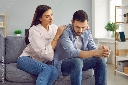Принти на полотні Young woman trying to apologize and make peace with her husband after quarrel sitting on sofa at home