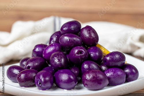 Kalamata olive with blueberries flavor. Purple olives on wood background. Close up