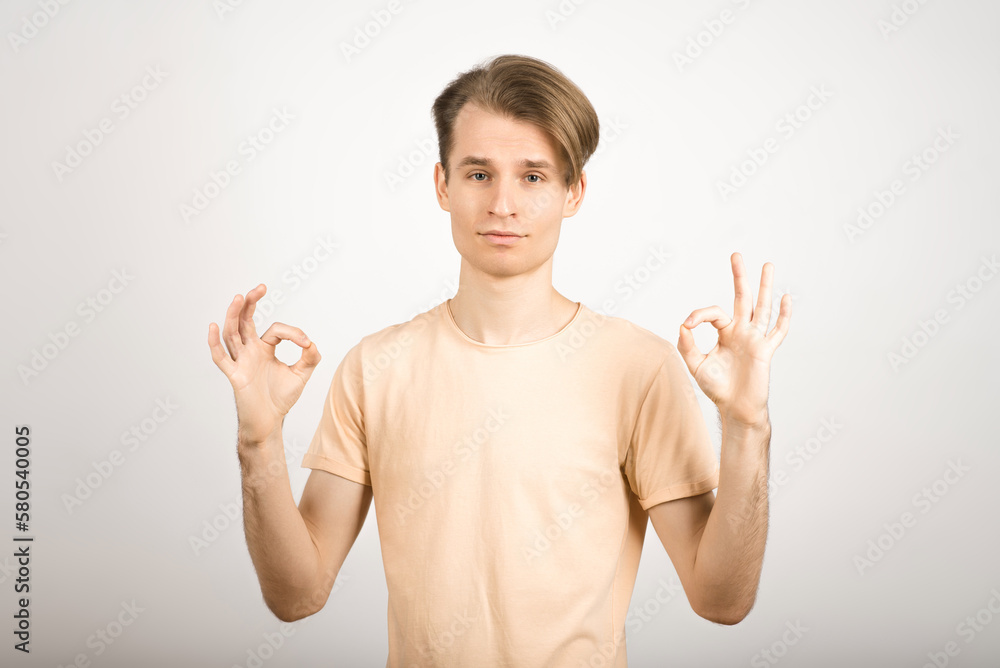 A happy guy shows an okay gesture on a white background. A happy guy shows an okay gesture on a white background.