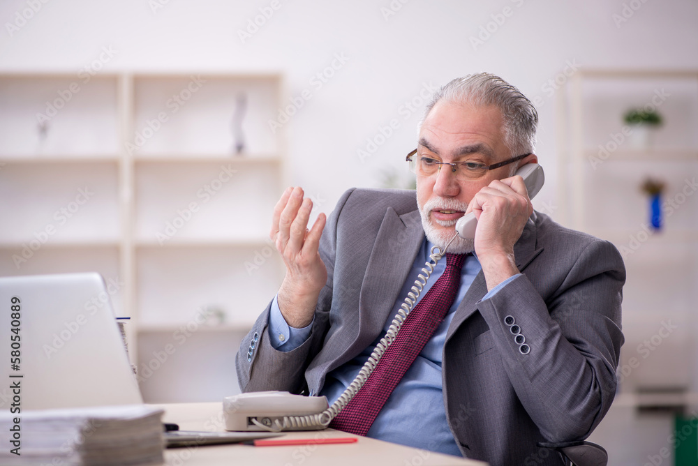 Old male employee working in the office Old male employee working in the office