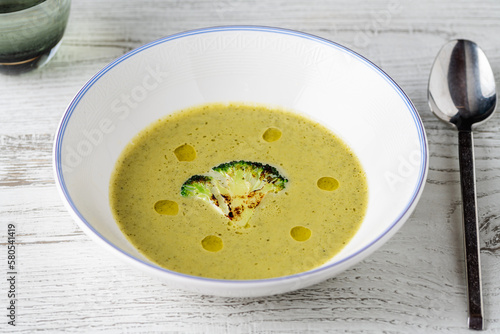 Healthy broccoli soup with a slice of grilled broccoli on a white porcelain plate