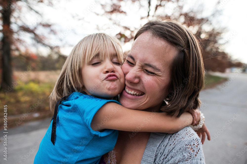 Daughter puckering while embracing happy mother on road Daughter puckering while embracing happy mother on road