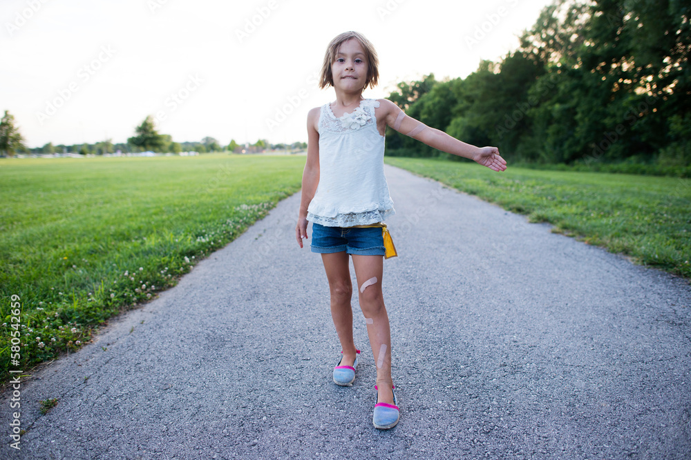 Portrait of girl showing bandages while standing on road against clear sky Portrait of girl showing bandages while standing on road against clear sky