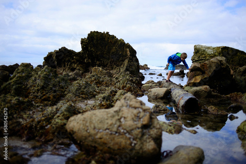 Boy searching something while standing on rocks at Laguna Beach photo