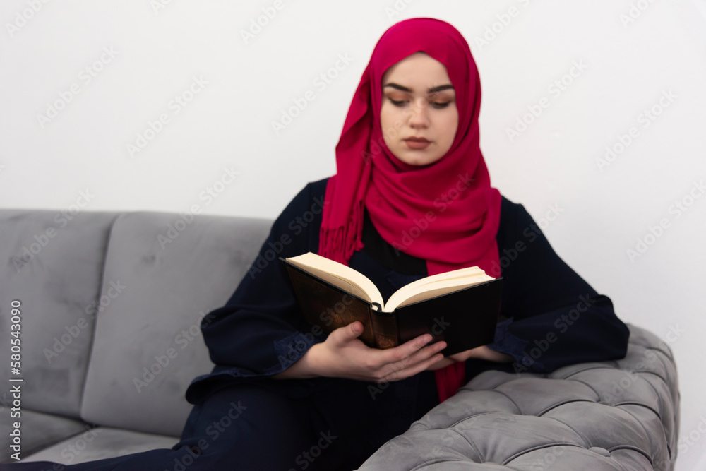 Young Woman Reading Koran While Sitting On Floor At Home Young Woman Reading Koran While Sitting On Floor At Home