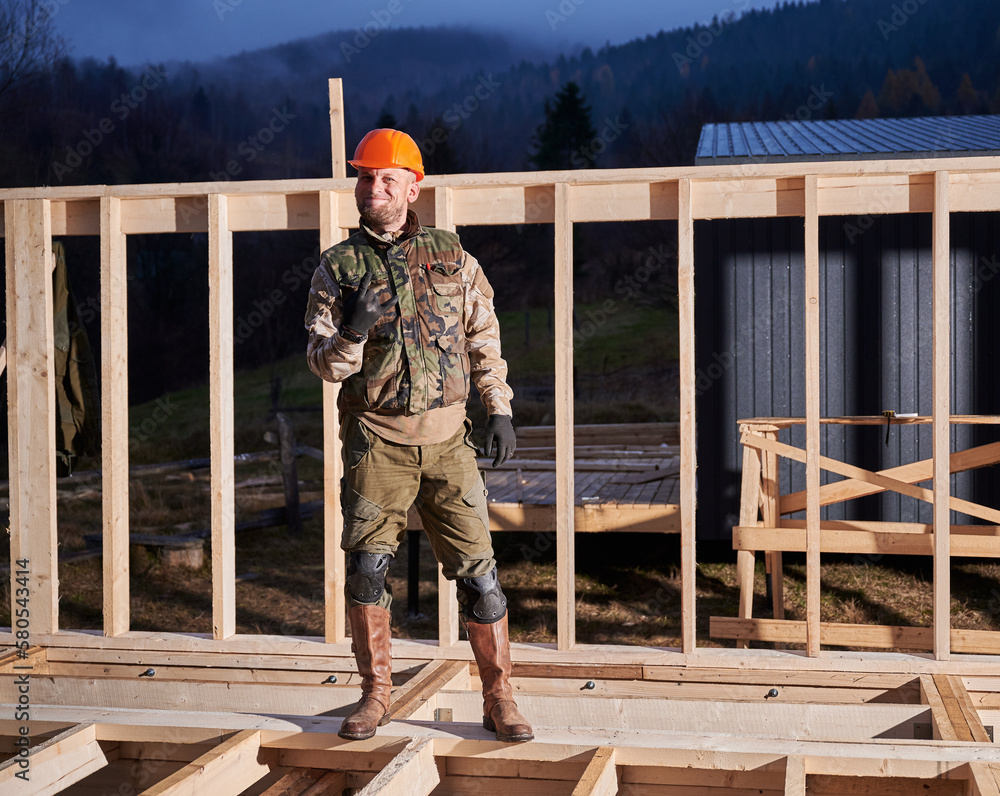 Male worker building wooden frame house. Man standing on construction ...