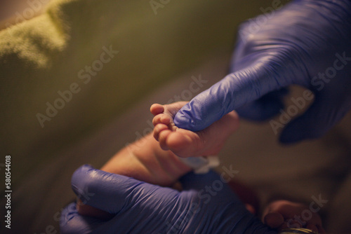 Cropped hands of pediatrician touching newborn baby's foot at hospital photo