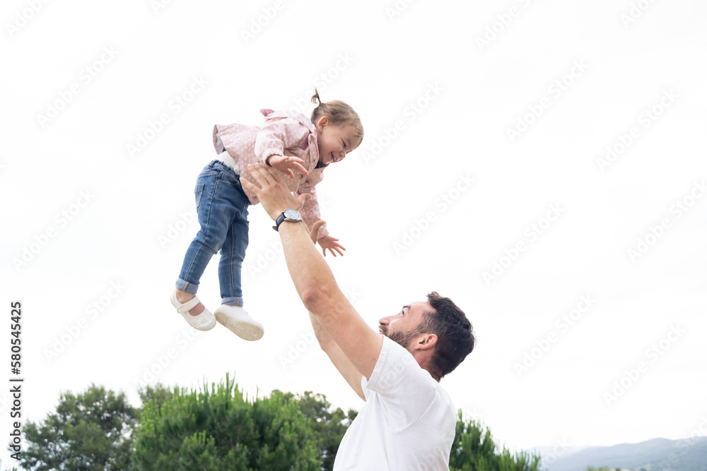Playful dad lifting on the air her little daughter Playful dad lifting on the air her little daughter