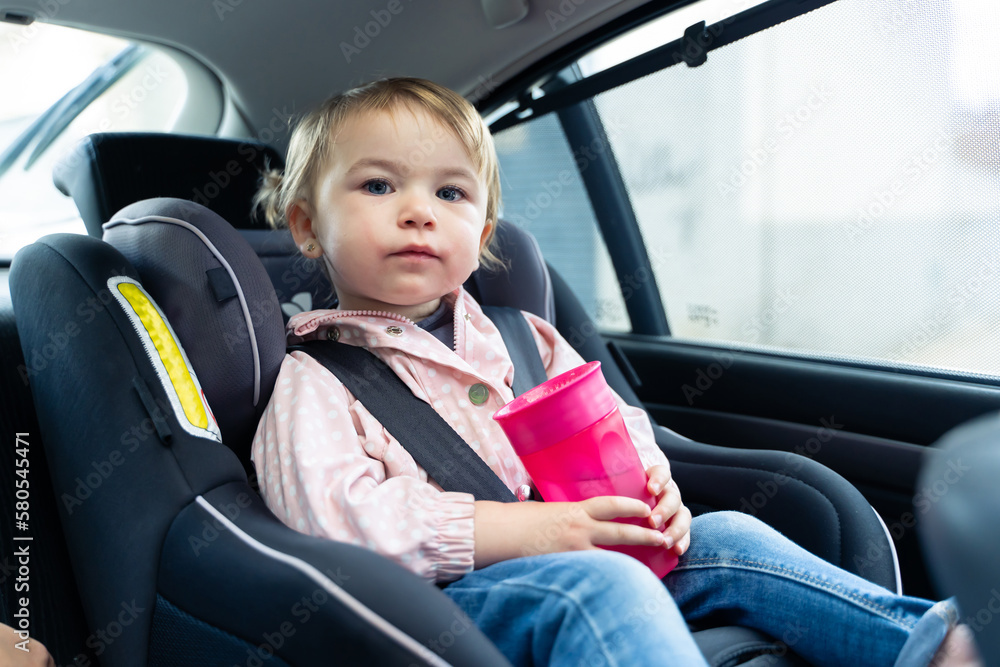 Girl looking at camera while drinking water in a car