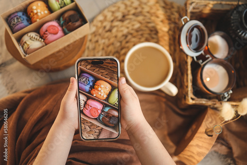 Girl taking a top-down photo of macaron box with various assortment using her phone