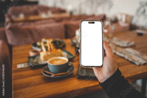 Girl holding a phone with a blank screen in a cafe, with food in the background