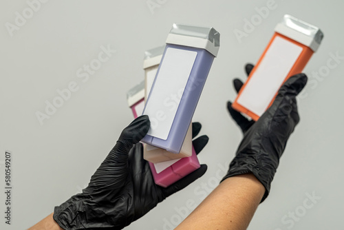 hand of a beautician holding fat-soluble wax cartridges for hair removal. photo