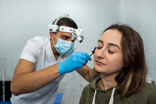 Advanced examination of a woman s ear using an otoscope at a doctor s appointment.
