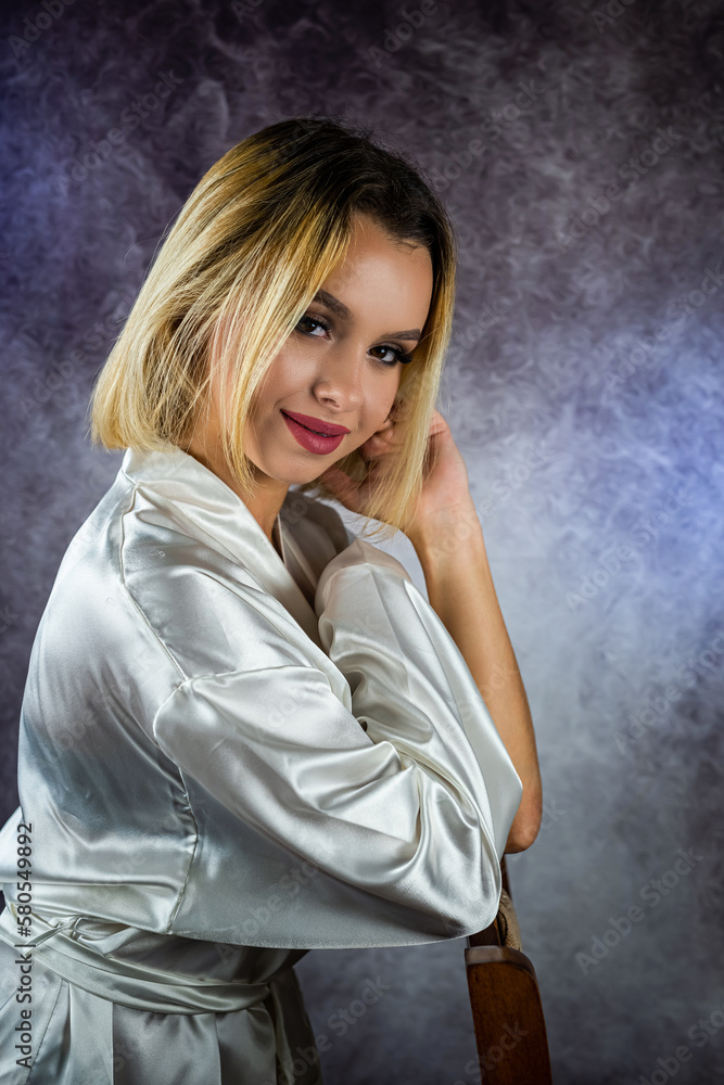 young slender blonde woman in a stylish dressing gown isolated on a beautiful background. young slender blonde woman in a stylish dressing gown isolated on a beautiful background.