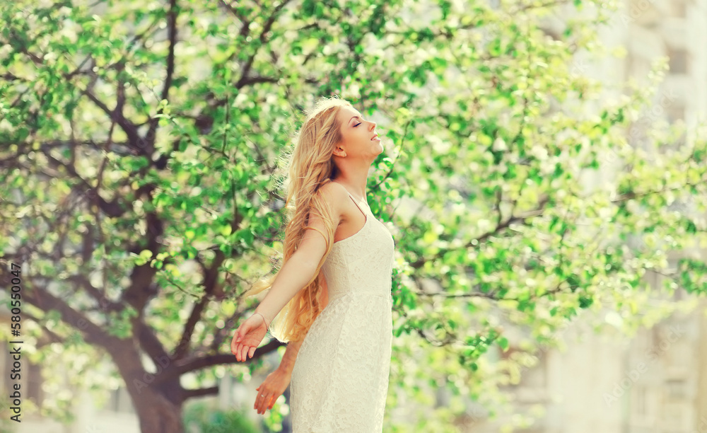 Beautiful blonde young woman enjoying smell in spring blooming garden Beautiful blonde young woman enjoying smell in spring blooming garden