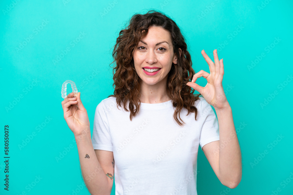 Young caucasian woman holding a envisaging isolated on blue background showing ok sign with fingers Young caucasian woman holding a envisaging isolated on blue background showing ok sign with fingers