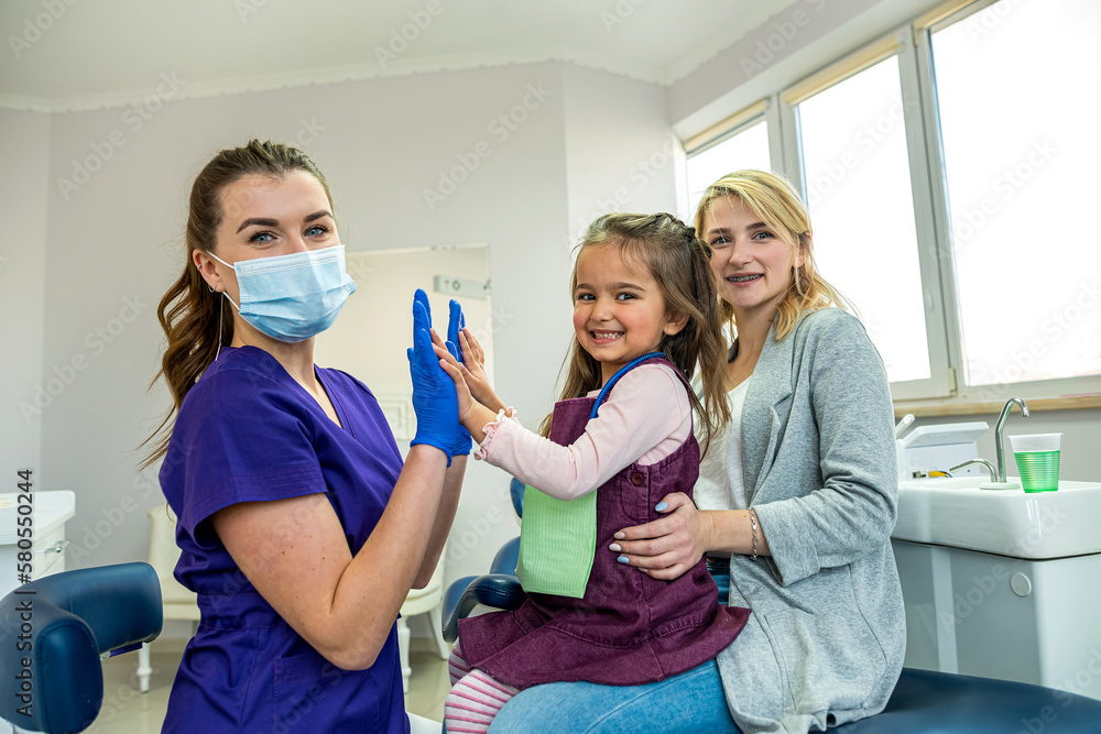 young dentist in special gloves and mom entertain a little girl. young dentist in special gloves and mom entertain a little girl.