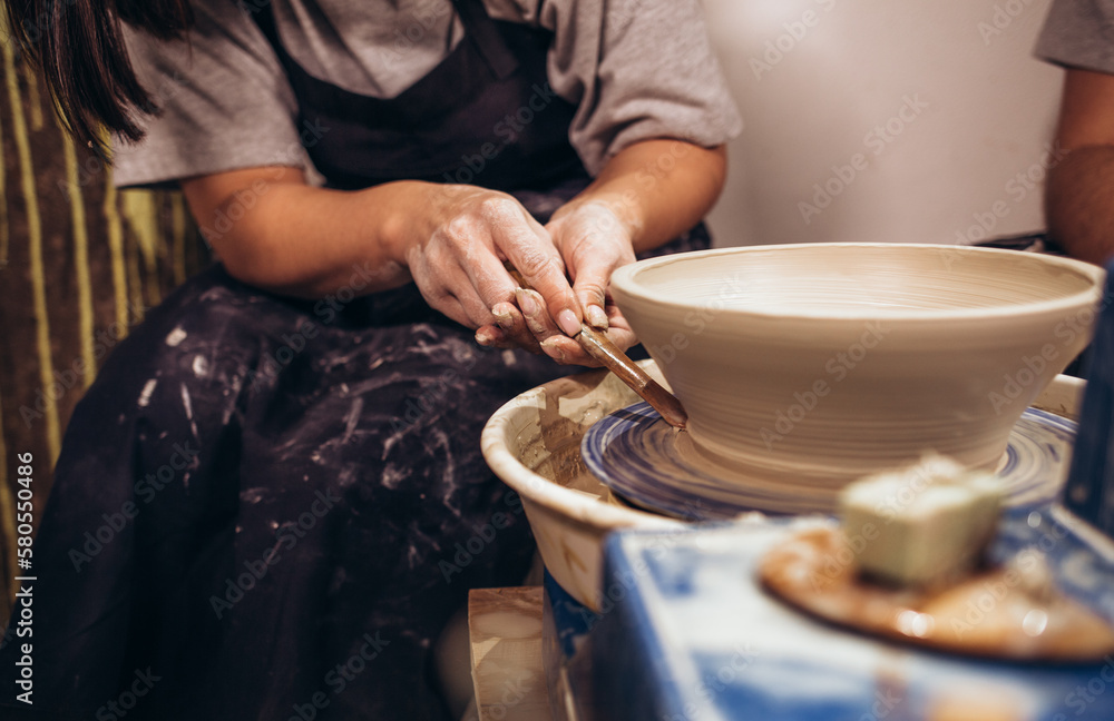 Woman hands working on pottery wheel and making a pot.