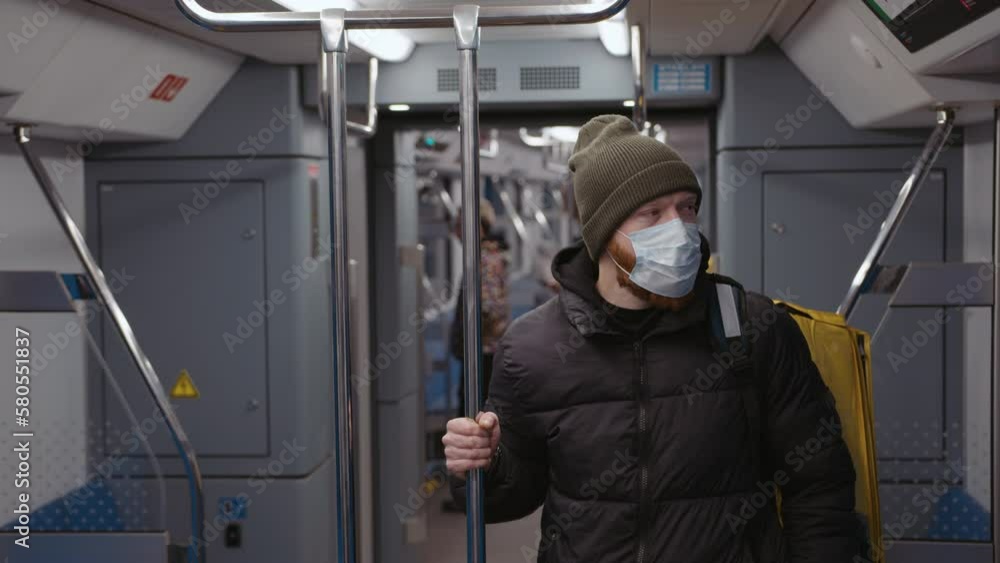 Delivery from restaurants. Portrait of a male courier with a medical mask on the background of a subway car Delivery from restaurants. Portrait of a male courier with a medical mask on the background of a subway car