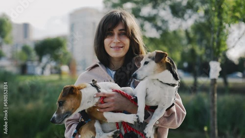 Portrait of the Beautiful Woman, Carrying Her Two Jack Russells Puppies and Looking Smiling at the Camera on the Local Lake and Park Background. People and Dogs Friendship Concept photo